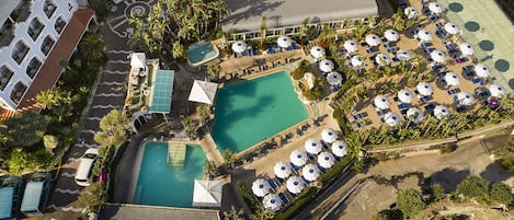 An aerial view of a resort with multiple swimming pools, sun loungers, and umbrellas.