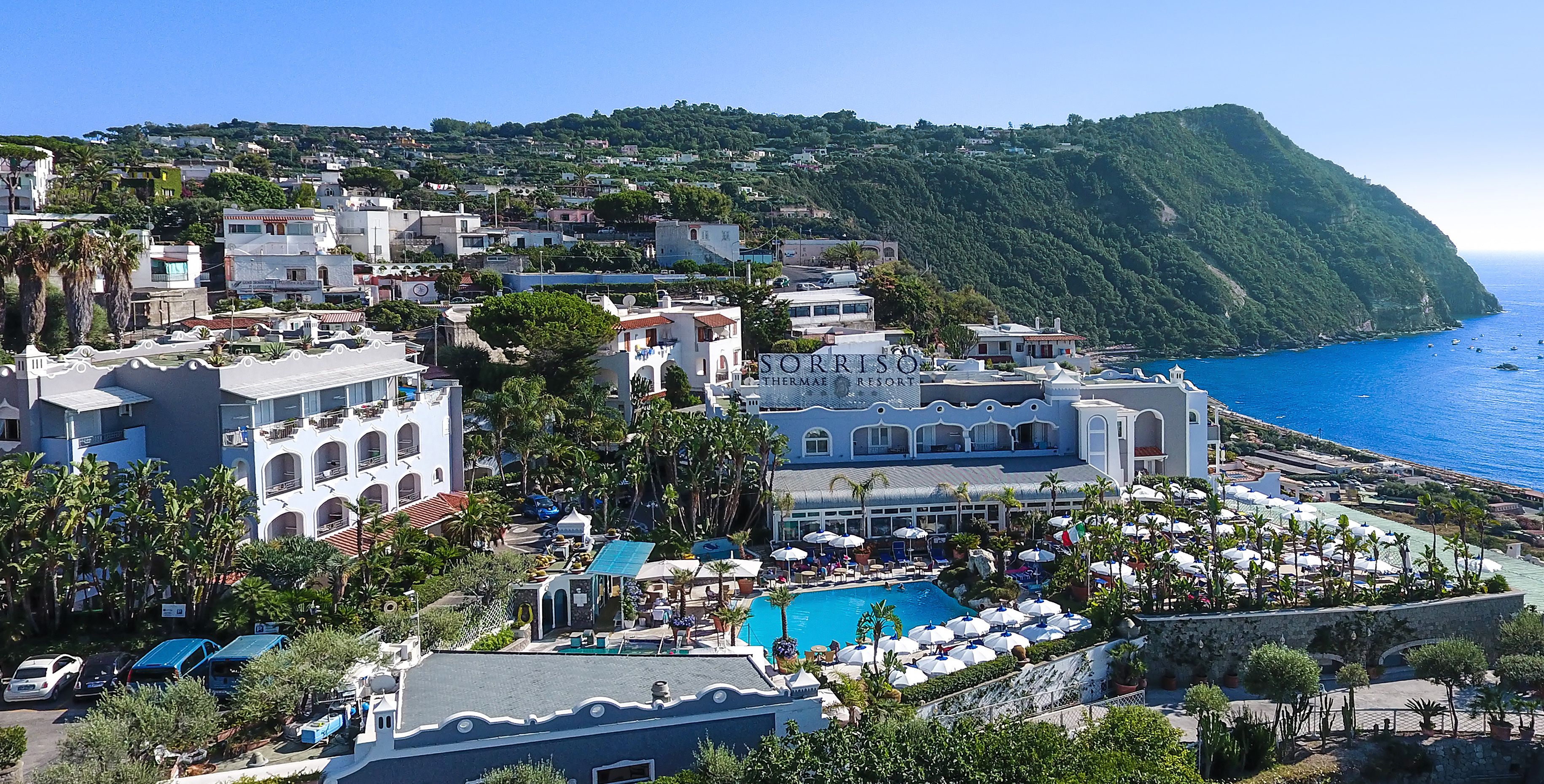 Un resort con piscina, sombrillas y vistas al mar.