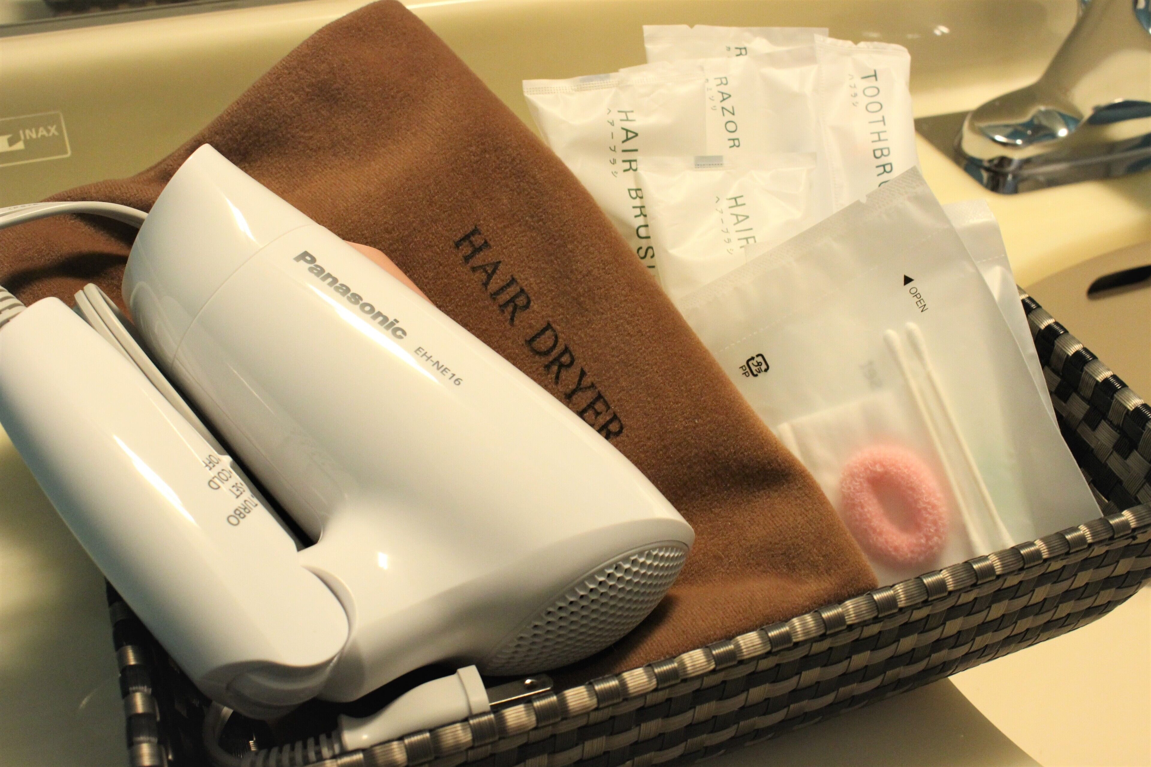 A bathroom sink with a hair dryer and toiletries.