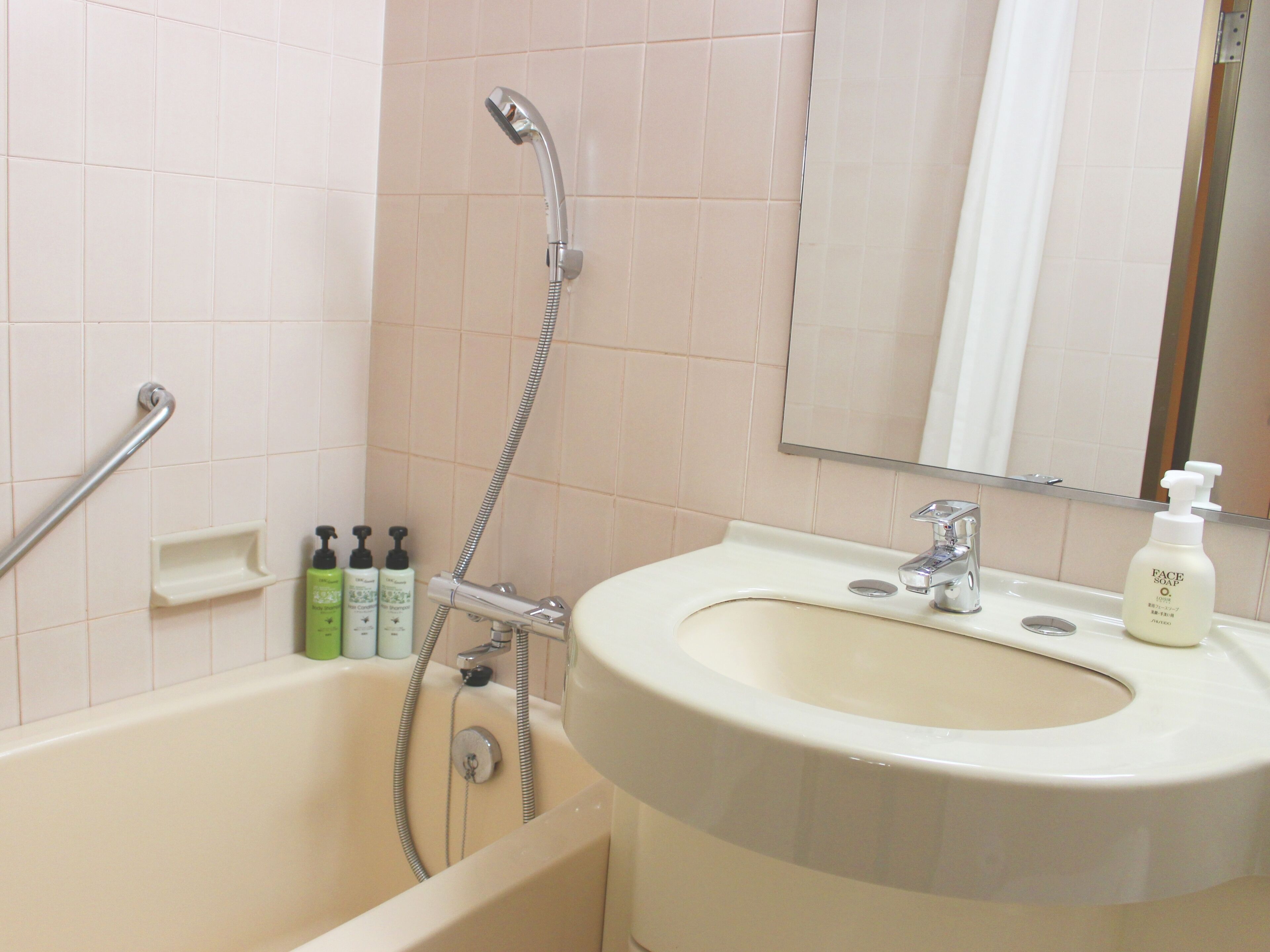 Un baño con bañera, lavamanos, espejo y artículos de aseo.