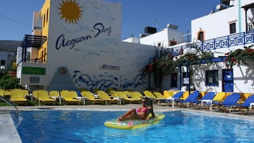 Relax by the pool surrounded by a vibrant mural depicting a sun and waves.