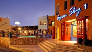 A hotel with a pool area, outdoor seating, and a neon sign. - Aegean Sky Hotel & Suites (Hersonissos)