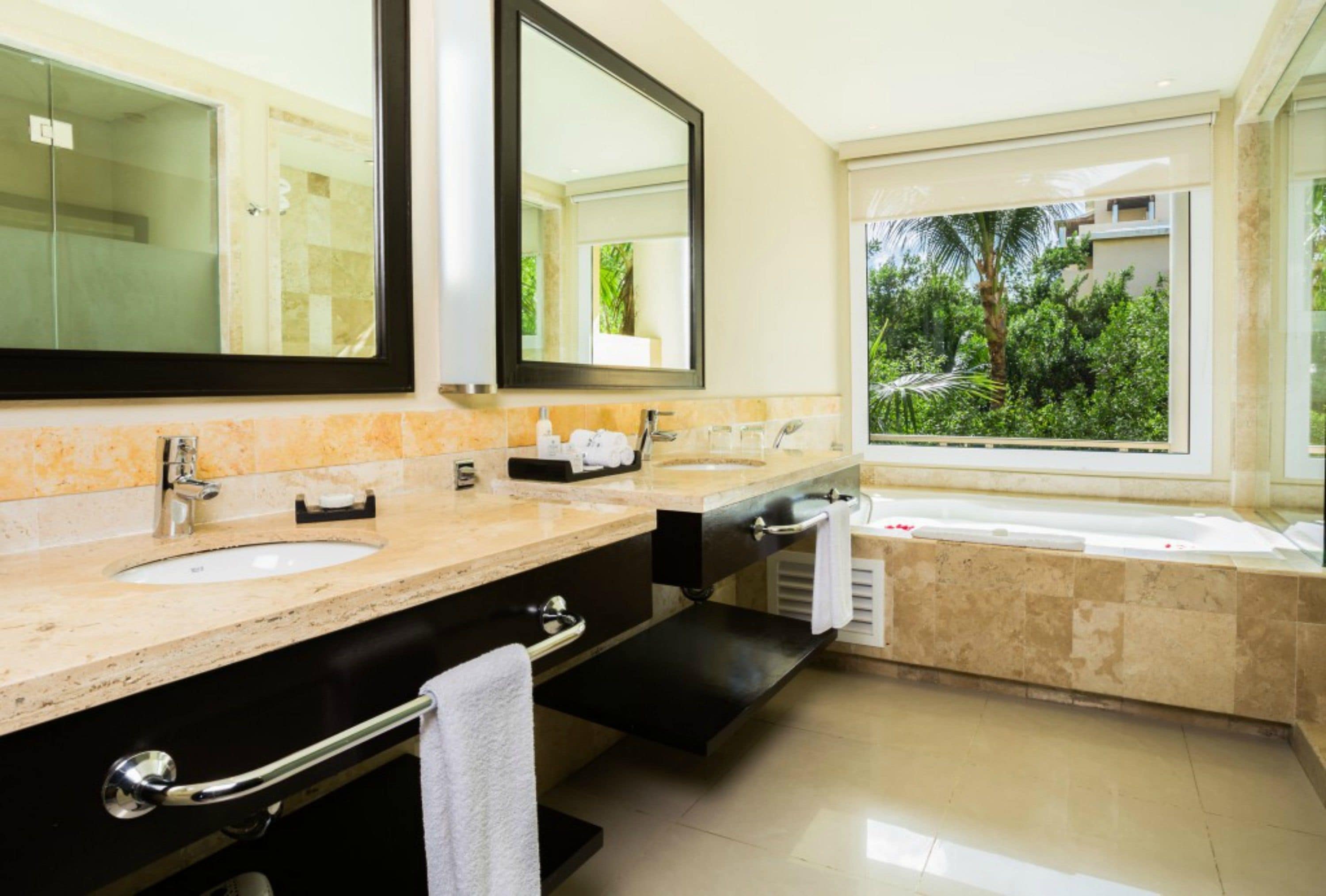 A modern bathroom with two sinks, a large mirror, and a bathtub.