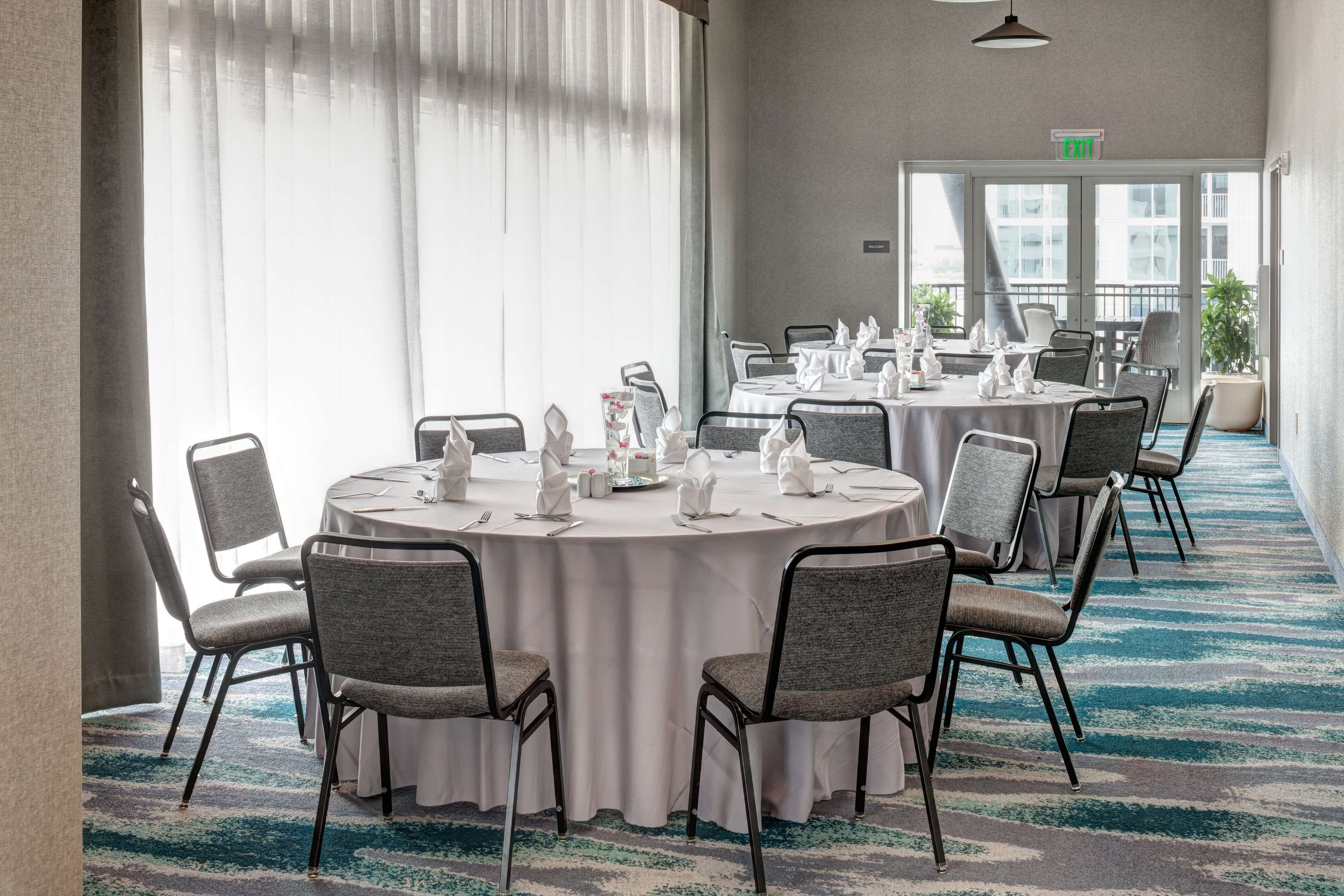 A conference room with round tables, grey upholstered chairs, and a blue carpet.