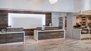 Een receptiegedeelte met een modern ontwerp, met houten receptiebalies en een groot verlicht scherm.