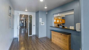 A hallway with wooden flooring, a wooden cabinet, and a mirror. - Extended Stay America Select Suites - Ogden (Ogden)