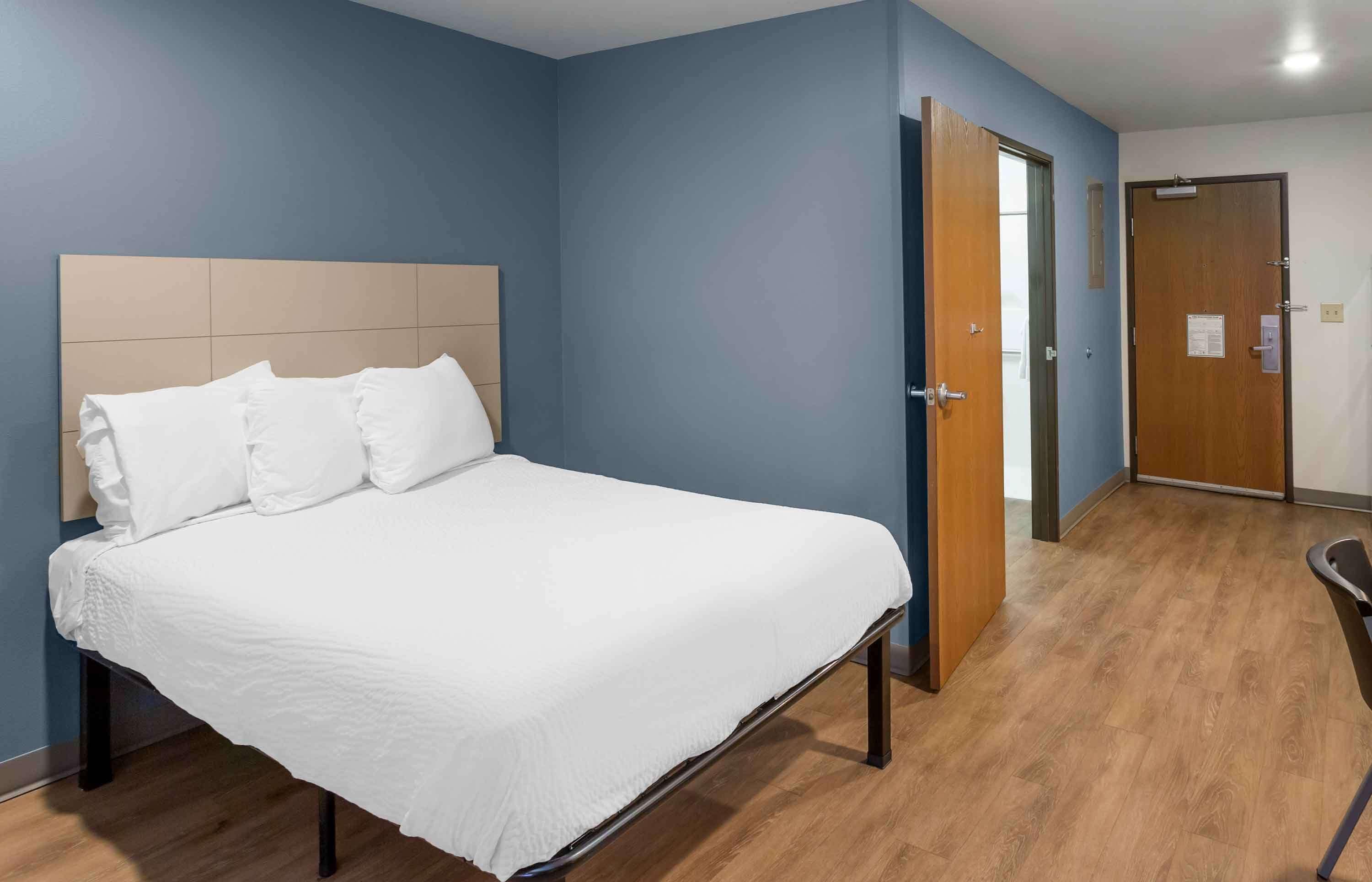 A hotel room with a large bed, wooden flooring, and a blue accent wall.