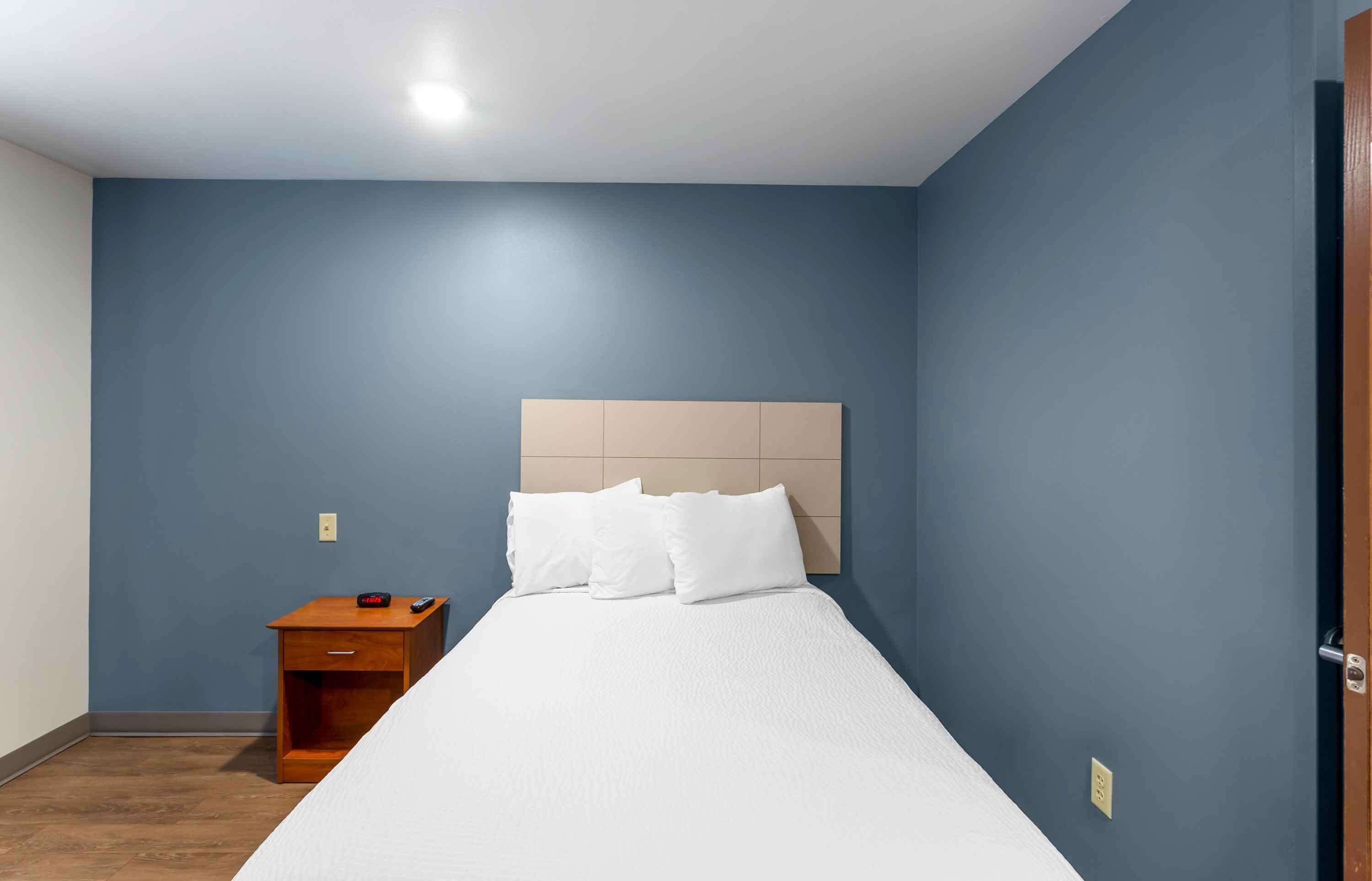 Un dormitorio con cama, mesita de noche y puerta de madera.