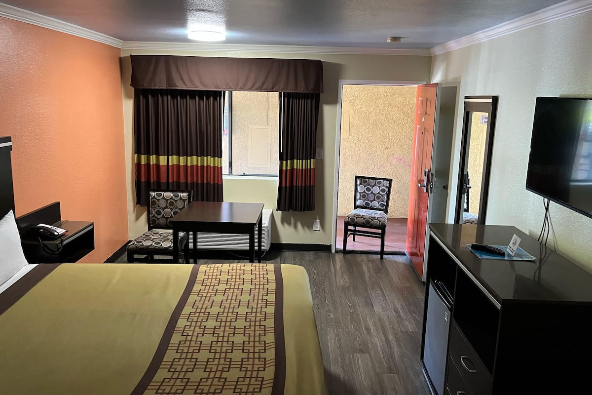 A hotel room with a bed, a desk, a chair, a television, and a window with curtains.
