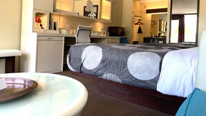 A hotel room with a bed, a desk, a chair, a microwave, a sink, and a mirror. - Oxford Inn Ozark (Ozark)