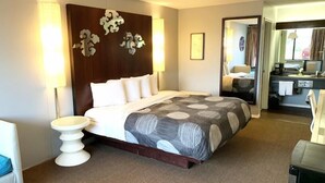 A hotel room with a bed, bedside table, and a view of the bathroom. - Oxford Inn Ozark (Ozark)