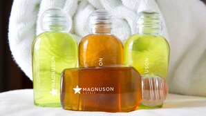 Drie flessen body lotion van Magnusun Hotels en een kleinere fles, allemaal met duidelijke etiketten, op een witte doek.