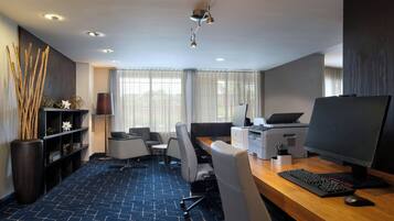 A modern office space with a desk, computer, printer, and seating area.
