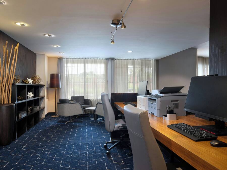A modern office space with a desk, computer, printer, and seating area.