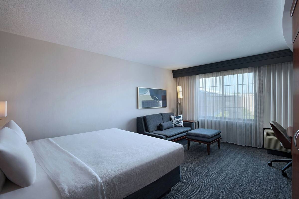 Una habitación de hotel con cama, sofá, escritorio y silla.