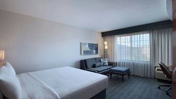 A hotel room with a bed, a sofa, a desk, and a chair.