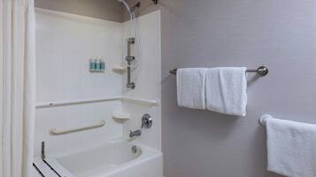 A bathroom with a bathtub, grab bars, a towel rack, and a showerhead.