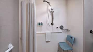 A bathroom with a shower, a grab bar, a wheelchair-accessible chair, and a towel rack.