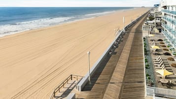 Un hotel frente al mar con un paseo marítimo de madera, mobiliario exterior y vistas al océano.