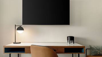 Een moderne tafel met een lamp, een zwarte houder en een kussen op een stoel.