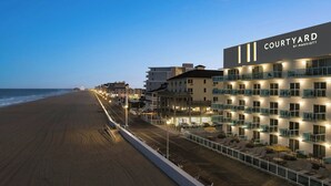Un hotel llamado 'Courtyard by Marriott' con vistas a la playa, asientos al aire libre y varios balcones.