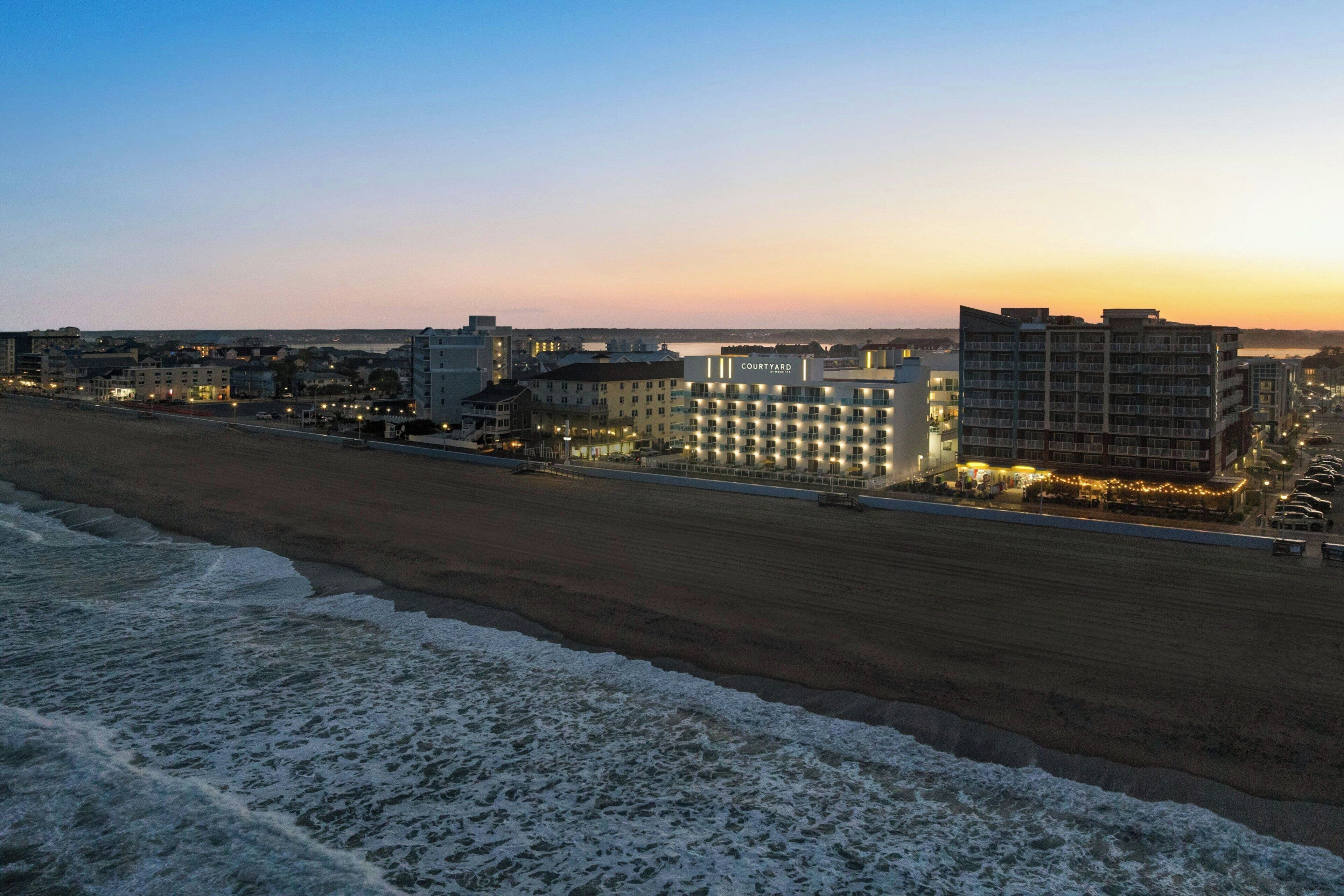 A coastal hotel with multiple floors, a beach view, and a well-lit exterior.