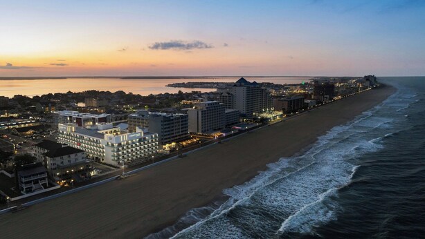 Un hotel costero con varias edificaciones, una playa y un muelle al fondo.