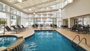 Una piscina interior con sillones de descanso y vistas a los balcones exteriores.