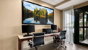 Un salón de conferencias con una gran televisión de pantalla plana, dos monitores y tres sillas de oficina.