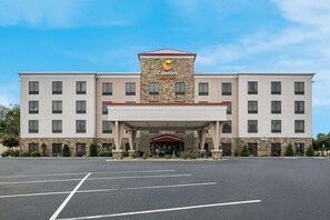 Ett Comfort Suites-hotell med en fasad av sten, många fönster och en överbyggd entré.