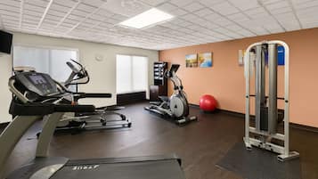 Un gimnasio con cintas de correr, elíptica, bicicleta estática y máquina de pesas.