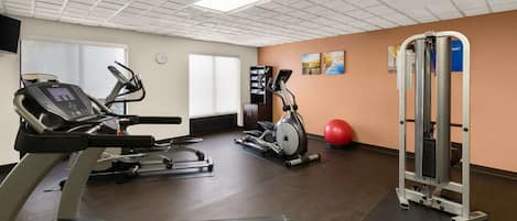 Un gimnasio con cintas de correr, elíptica, bicicleta estática y máquina de pesas.