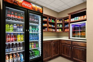 Una cocina con dos refrigeradores llenos de bebidas, armarios de madera y un microondas.