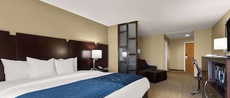Quarto de hotel com uma cama grande, uma escrivaninha, uma cadeira, uma TV e um minibar.