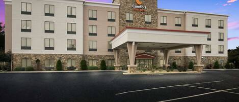Un hotel Comfort Suites con un diseño moderno, que cuenta con una entrada central y varios pisos.