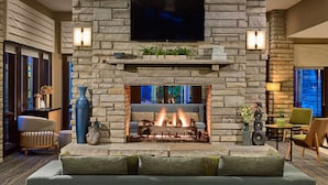 A stone fireplace with a flat-screen TV above it, flanked by two wall sconces.