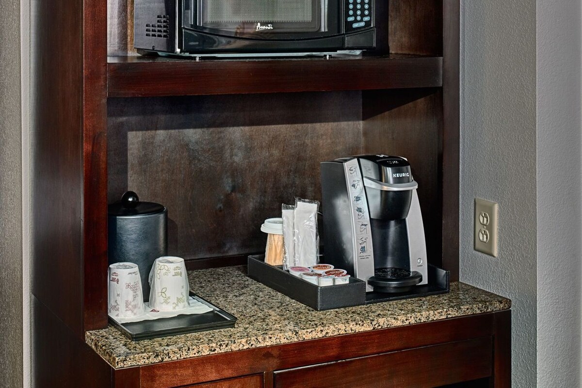 A kitchenette with a microwave, coffee maker, and refrigerator.
