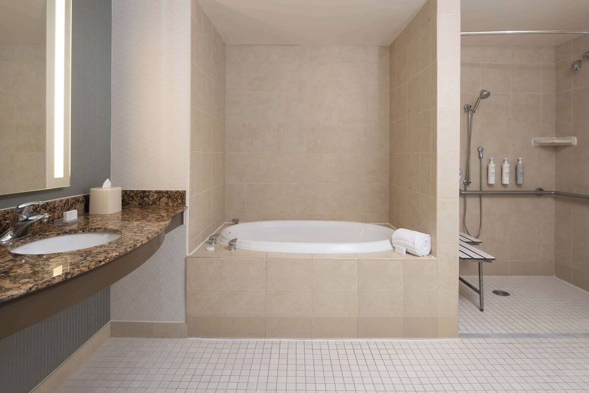 Un baño moderno con dos lavamanos, una bañera grande y una ducha a ras de suelo.