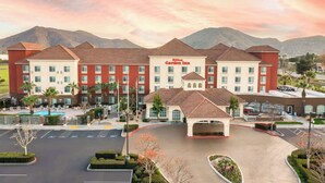Ein Hilton Garden Inn mit Pool, mehreren Etagen und einer Bergkulisse.