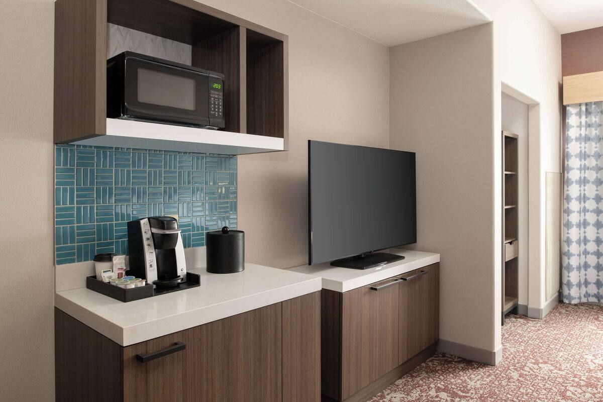 Una cocina compacta equipada con microondas, cafetera y televisor de pantalla plana.