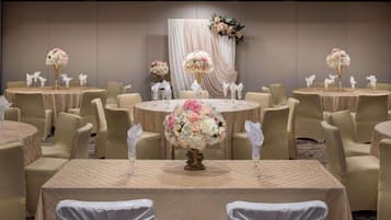 A banquet hall with round tables, each with a floral centerpiece and white napkins.