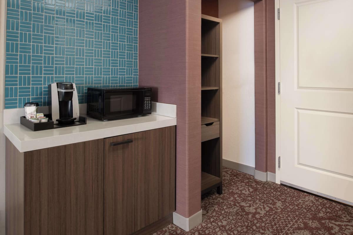 Una kitchenette equipada con cafetera, microondas y armarios para guardar.
