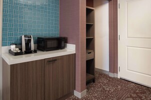 Una kitchenette equipada con cafetera, microondas y armarios para guardar.