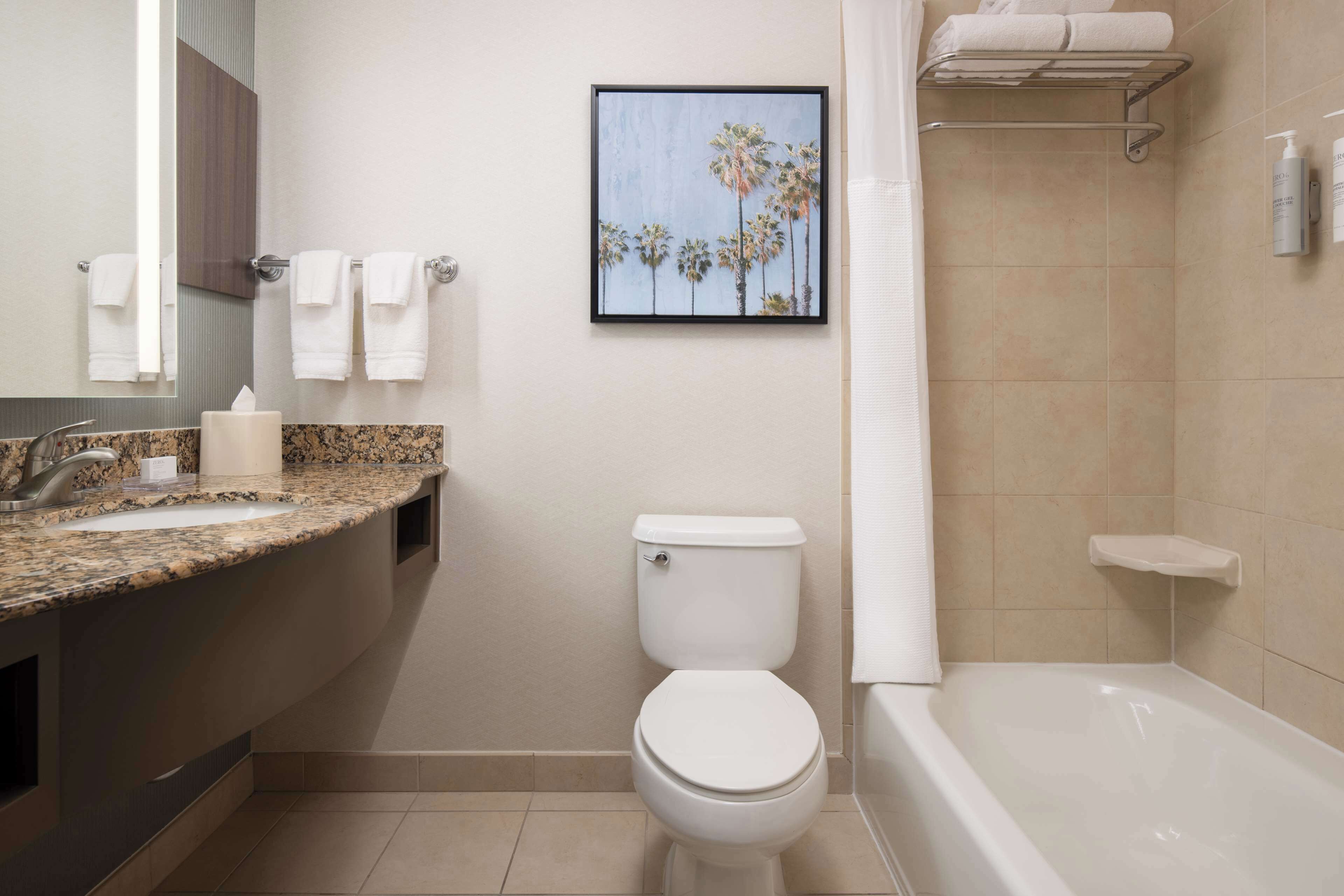 Un baño moderno con lavamanos de granito, inodoro y bañera.