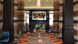 A long dining table with leather chairs, a chandelier, and a kitchen in the background. - Hilton Garden Inn Clovis (Clovis)