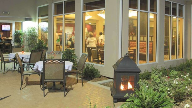 A hotel exterior with a dining area, outdoor seating, and a fire feature. - Hilton Garden Inn Clovis (Clovis)