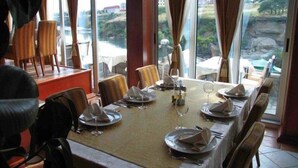 Une table à manger dressée pour six personnes, avec vue sur un paysage rocheux grâce à de grandes fenêtres.