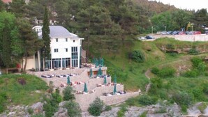 Un hôtel doté d’une terrasse extérieure donnant sur un plan d’eau, entouré de verdure et de collines.