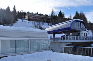 Un bâtiment enneigé, avec une passerelle couverte et un télésiège en arrière-plan.