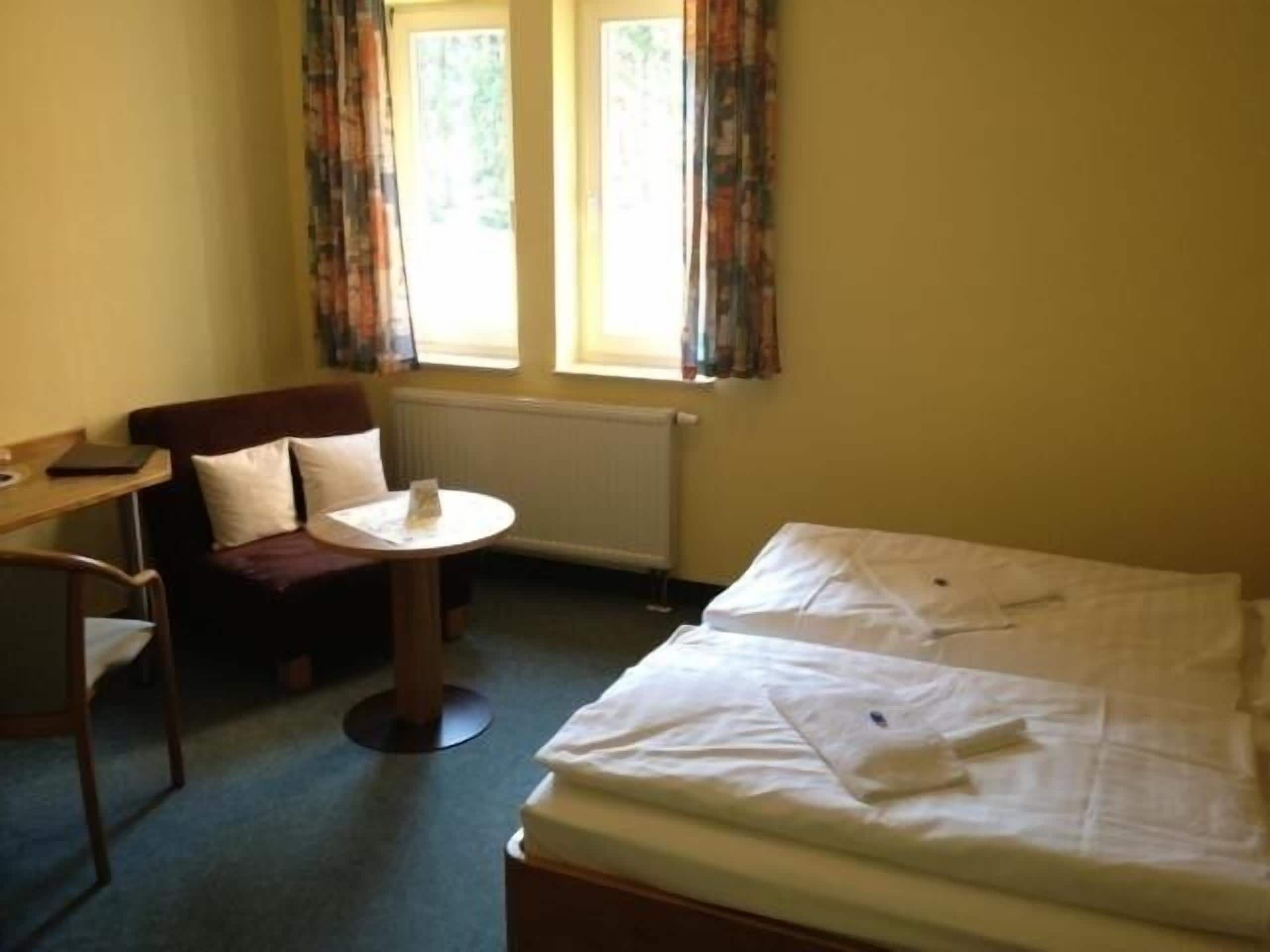 Una habitación de hotel con cama, escritorio, silla y una pequeña mesa.
